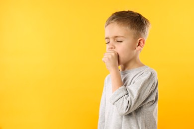 Photo of Sick boy coughing on yellow background, space for text. Cold symptoms