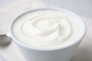 Delicious natural yogurt in bowl on table, closeup