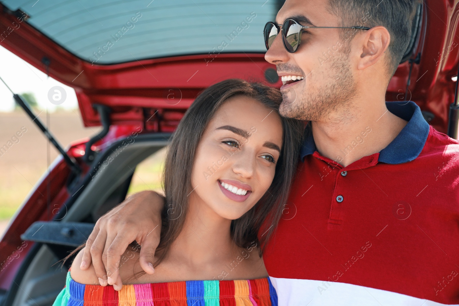 Photo of Happy young couple standing near car in shade