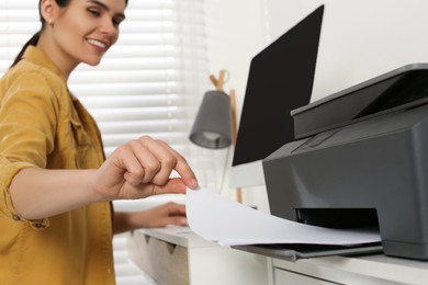 Photo of Woman using modern printer at workplace indoors, selective focus