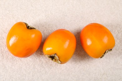 Delicious ripe persimmons on light textured table, top view