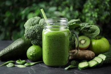 Photo of Delicious green juice and fresh ingredients on black table