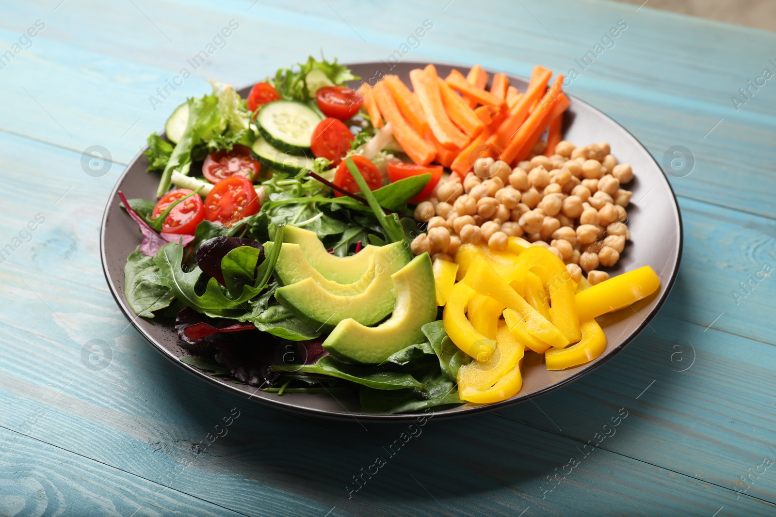 Photo of Balanced diet and vegetarian foods. Plate with different delicious products on light blue wooden table