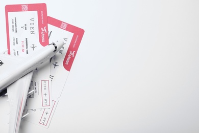 Photo of Toy airplane and tickets on white background, flat lay with space for text. Travel agency concept