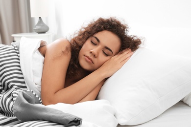 Young African-American woman sleeping on soft pillow at home. Bedtime