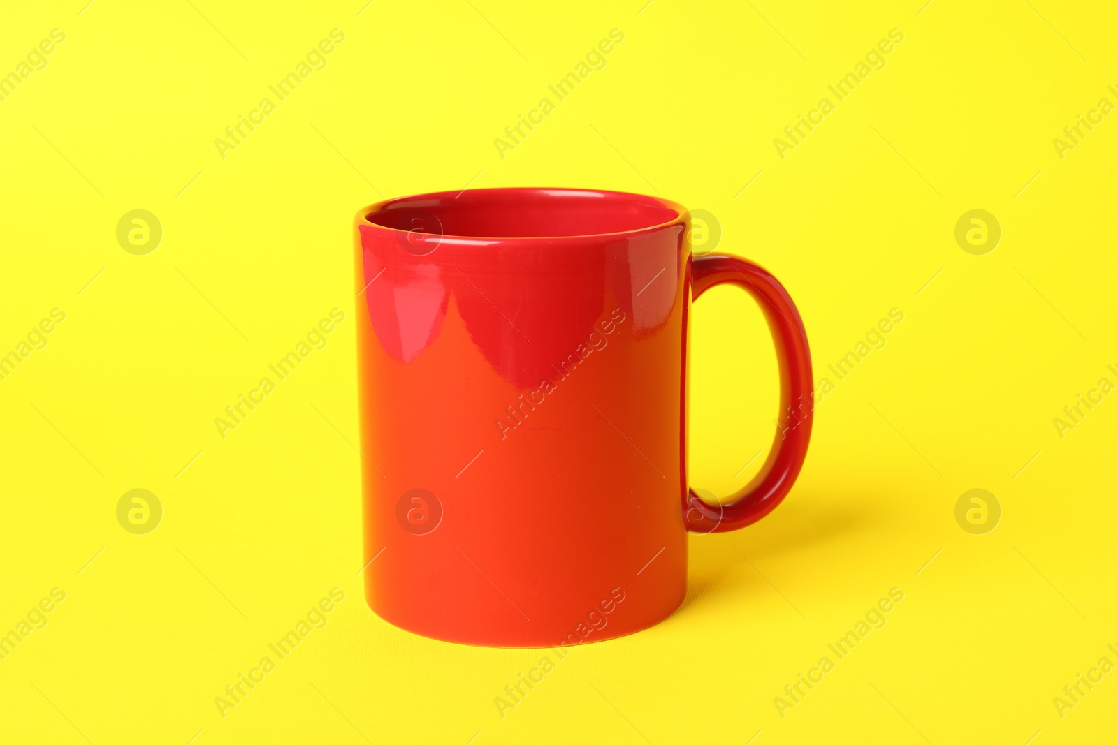 Photo of One red ceramic mug on yellow background