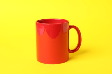 Photo of One red ceramic mug on yellow background