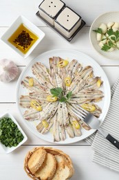 Tasty pickled anchovies served on white wooden table, flat lay