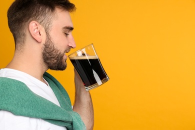 Photo of Handsome man with cold kvass on yellow background, space for text. Traditional Russian summer drink