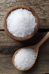 Photo of Organic salt in bowl and spoon on wooden table, flat lay