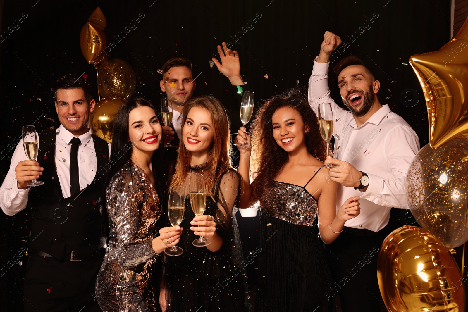 Photo of Happy friends with glasses of sparkling wine celebrating New Year on black background
