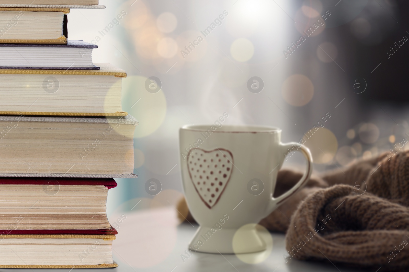 Image of Stack of books and cup on table indoors. Bokeh effect 