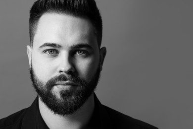 Portrait of handsome bearded man on grey background, space for text. Black and white effect