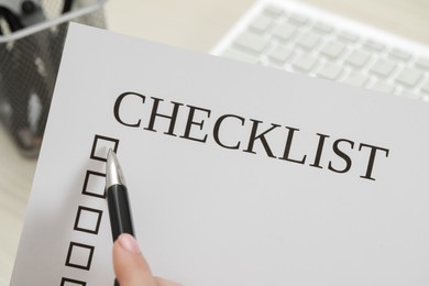 Photo of Woman filling Checklist with pen at workplace, closeup