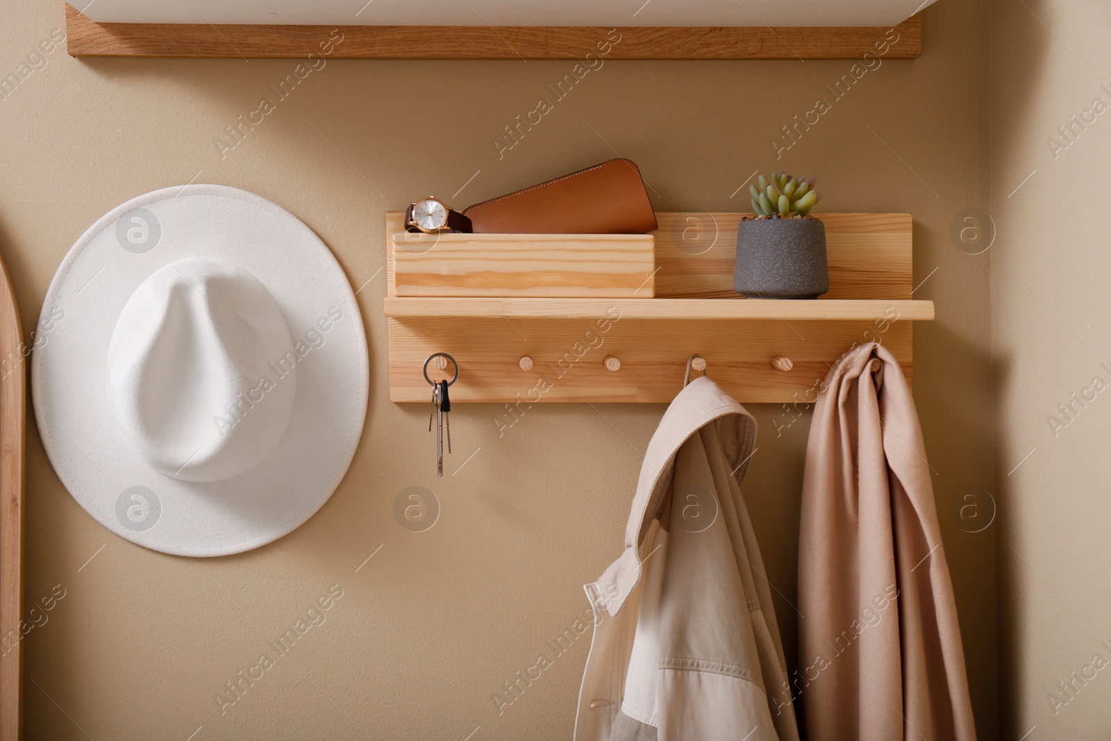 Photo of Hallway interior with stylish accessories and wooden hanger for keys on beige wall