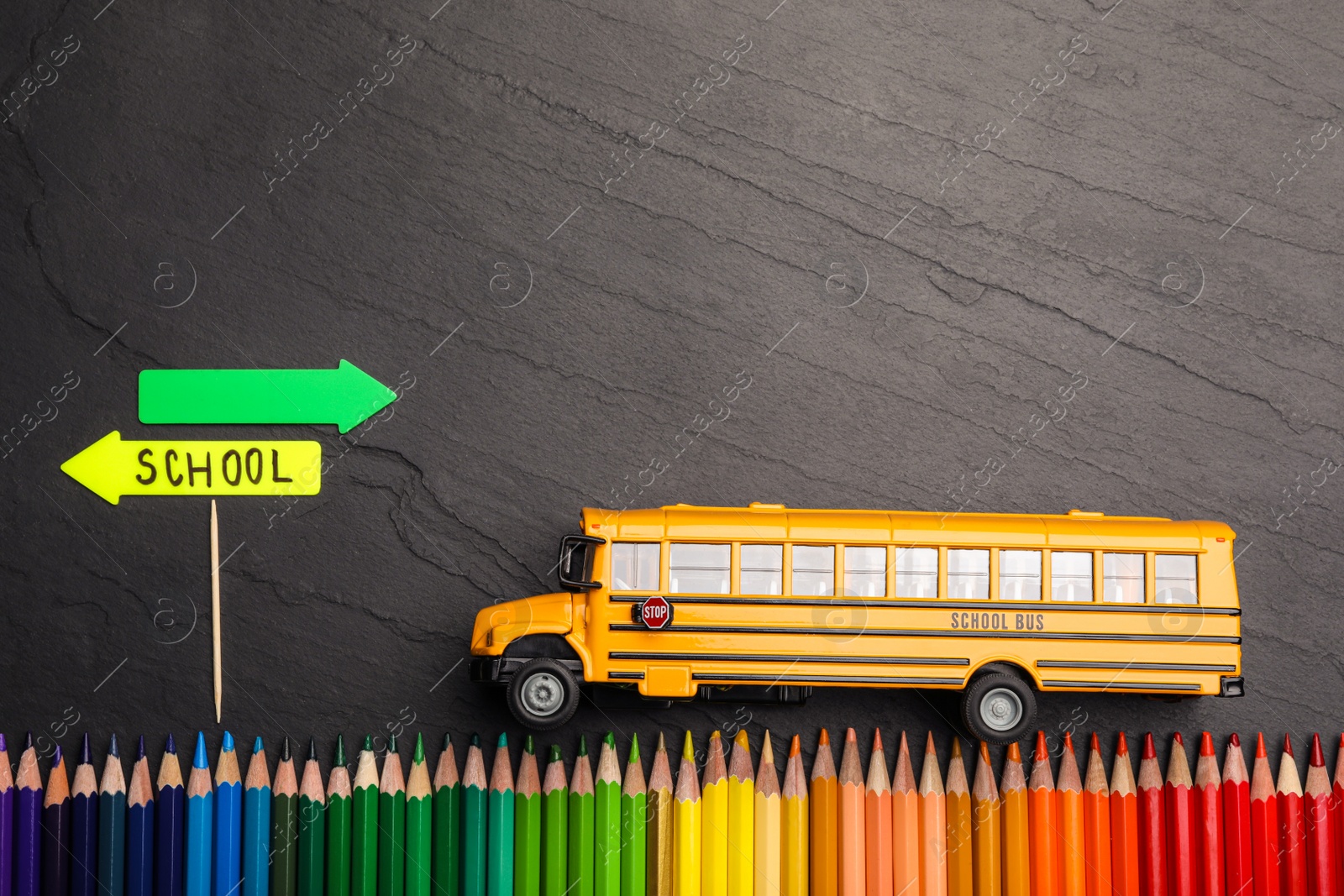 Photo of Flat lay composition with yellow school bus model on black background. Transport for students