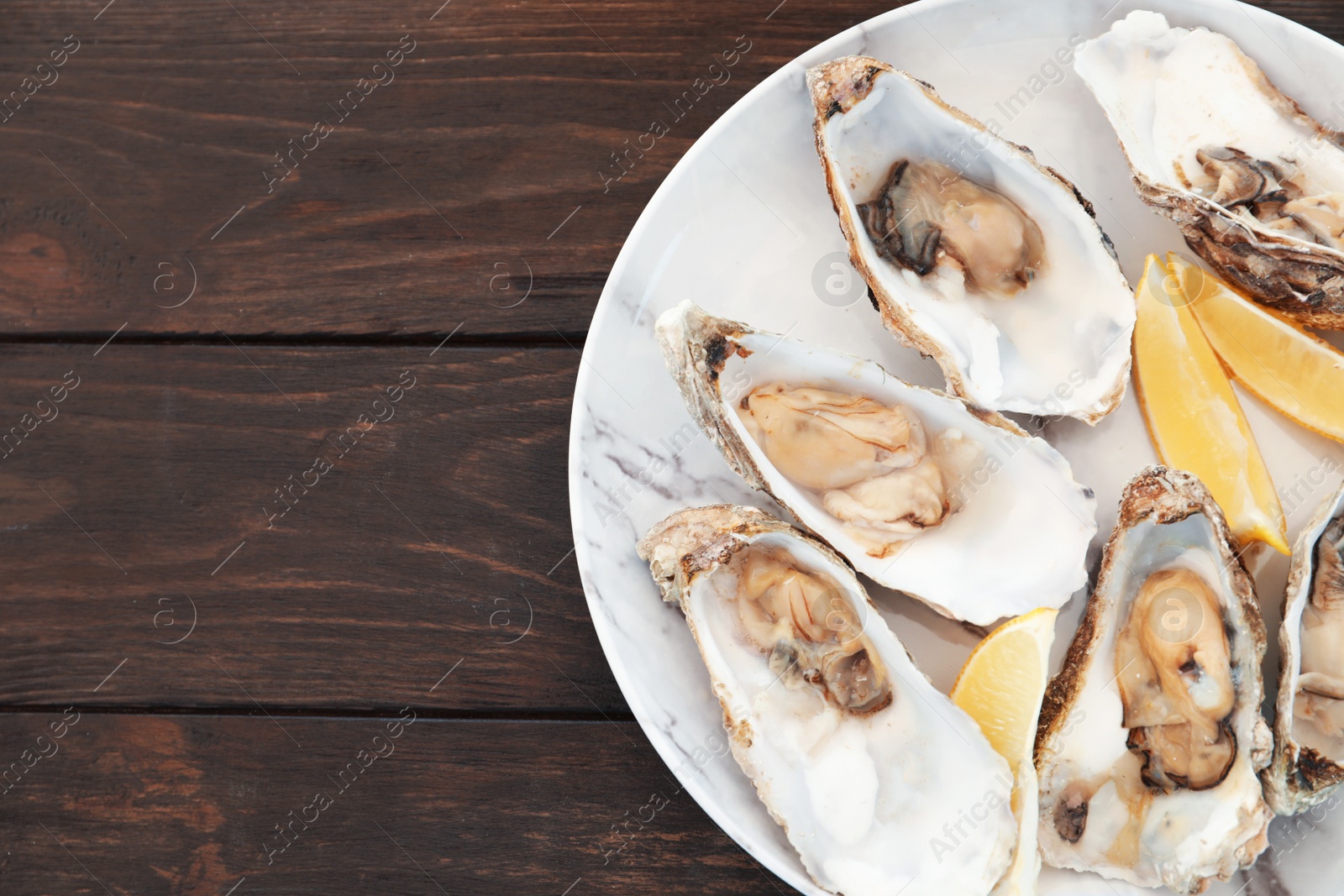 Photo of Fresh oysters with cut juicy lemon and space for text on table, top view