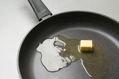 Photo of Frying pan with melting butter on grey table, closeup