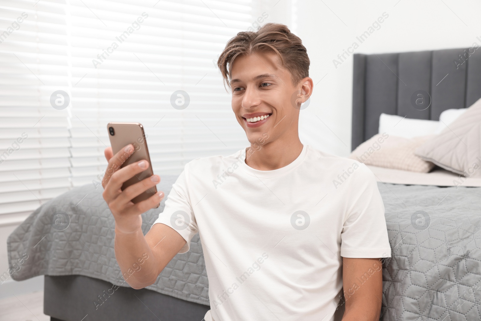 Photo of Happy young man having video chat via smartphone indoors