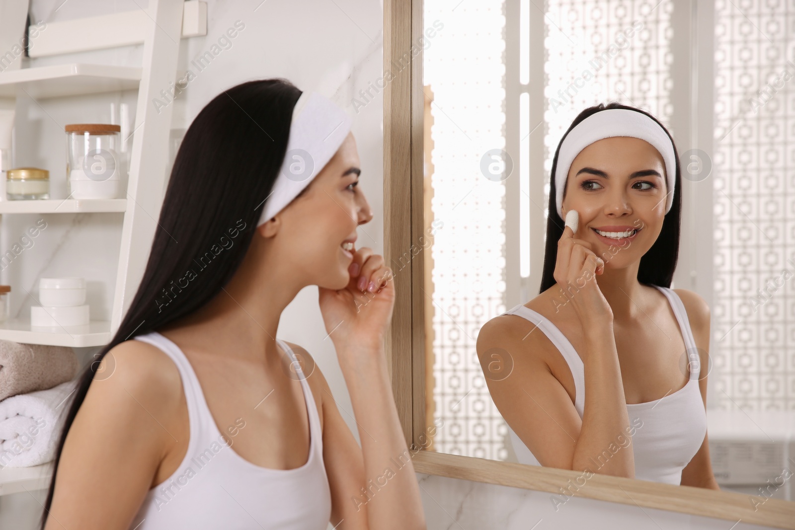 Photo of Woman using silkworm cocoon in skin care routine near mirror at home