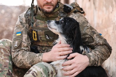 Photo of Ukrainian soldier hugging stray dog outdoors, closeup