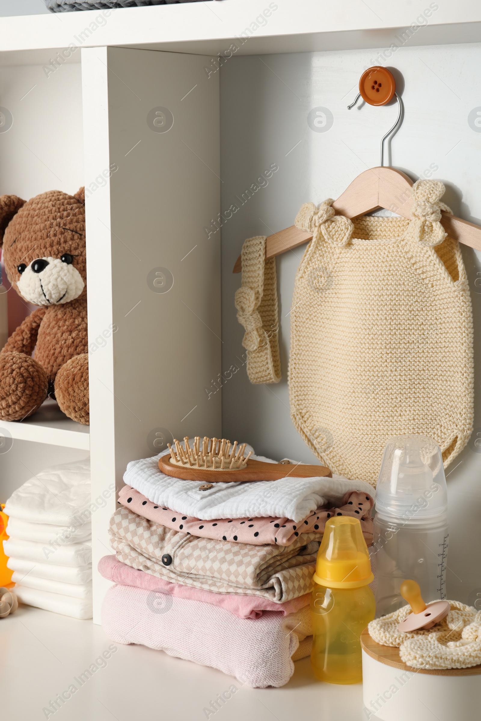 Photo of Baby clothes, toy and accessories on white rack