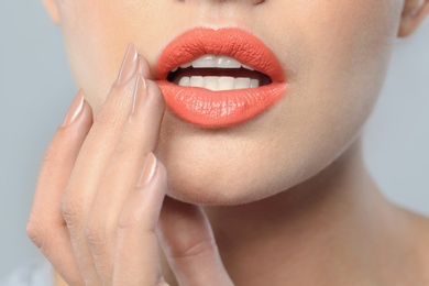 Young woman wearing beautiful lipstick on gray background, closeup