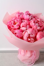 Bouquet of beautiful pink peonies on table near white wall