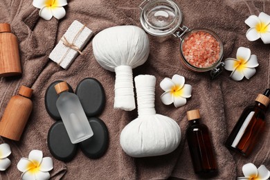 Photo of Flat lay composition with herbal massage bags and other spa products on brown towel