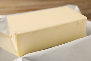 Photo of Block of tasty butter in wrap, closeup