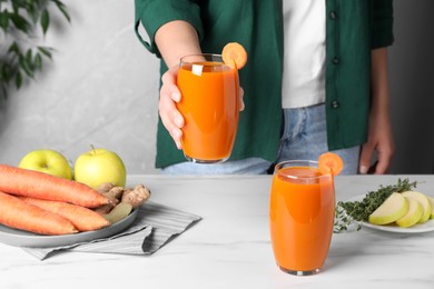 Photo of Woman holding glass with carrot juice, closeup