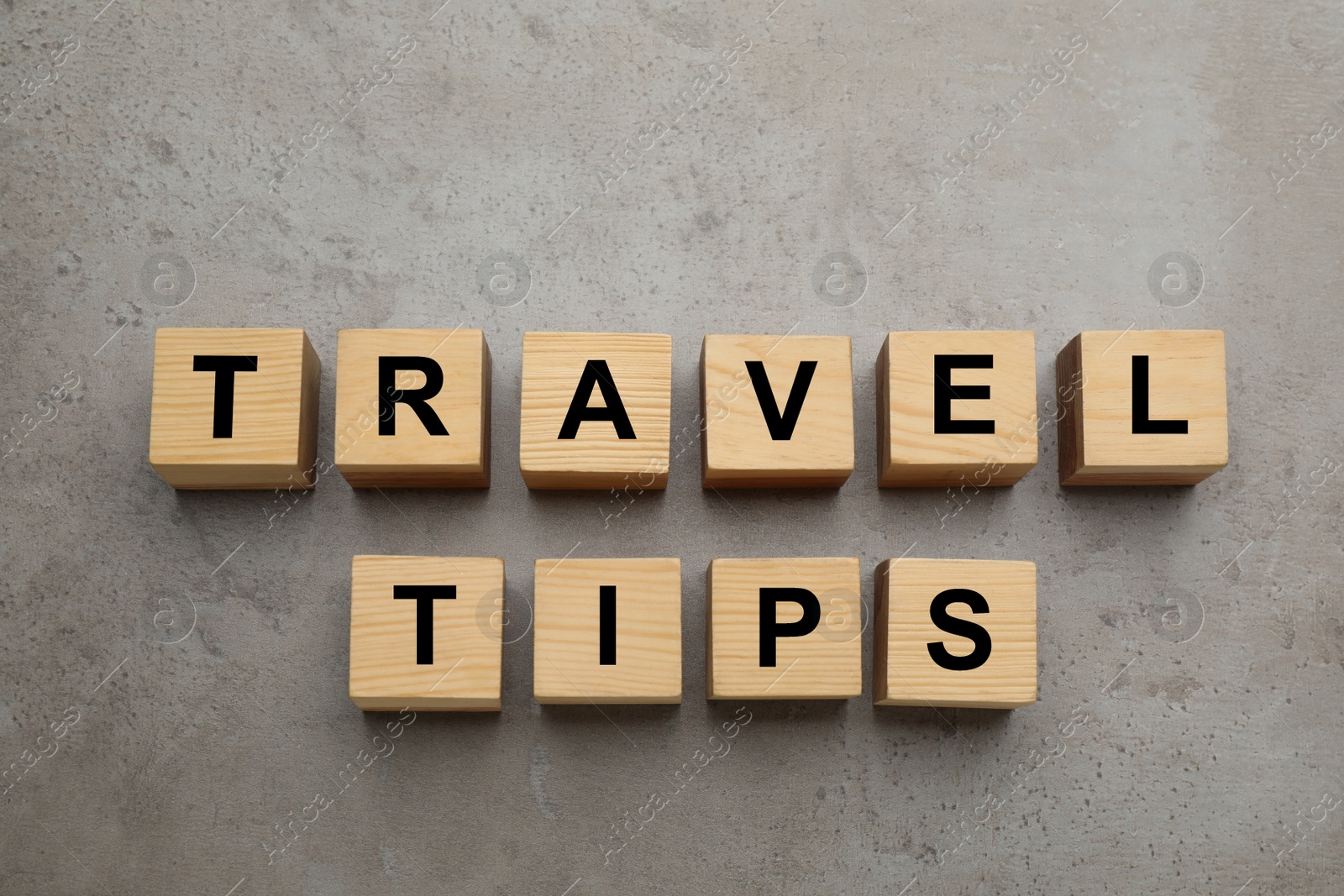 Photo of Phrase Travel Tips made with wooden cubes on grey table, flat lay