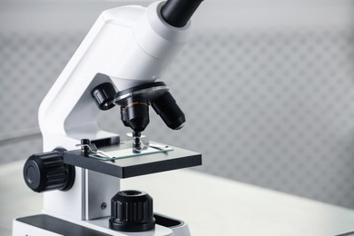 Photo of Modern medical microscope on metal table in laboratory, closeup. Space for text