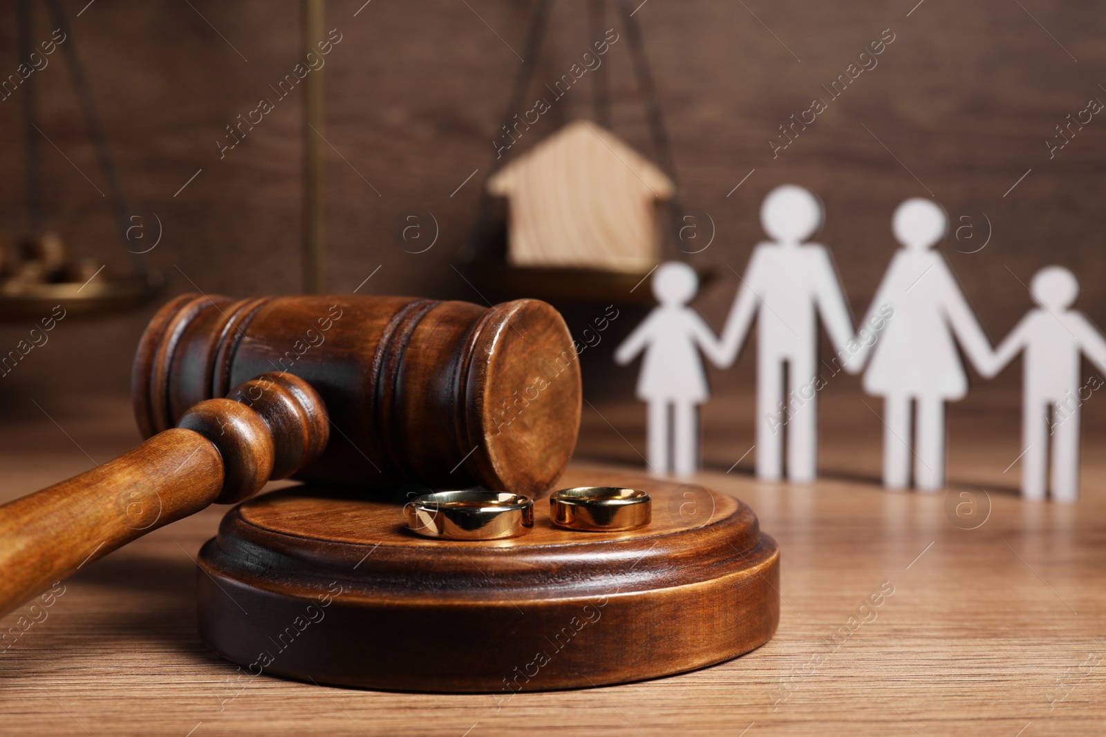 Photo of Divorce concept. Gavel and wedding rings on wooden table, space for text