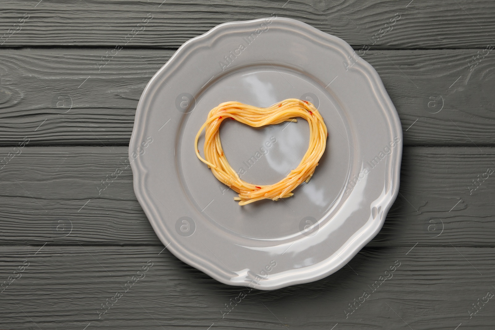 Photo of Heart made with spaghetti on grey wooden table