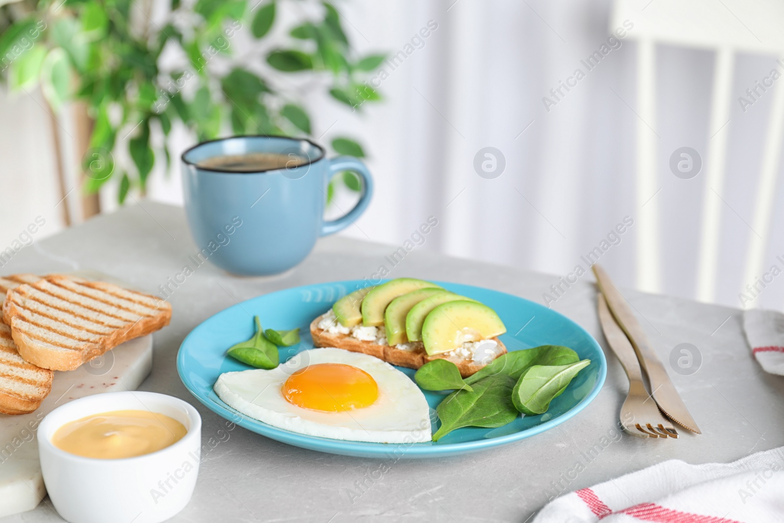 Photo of Romantic breakfast with heart shaped fried egg served on light grey kitchen table