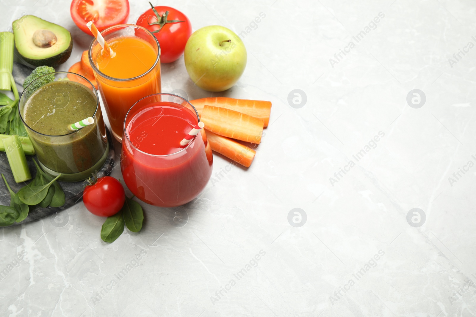 Photo of Delicious vegetable juices and fresh ingredients on light grey table. Space for text