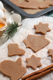 Raw Christmas cookies and cinnamon on table, closeup