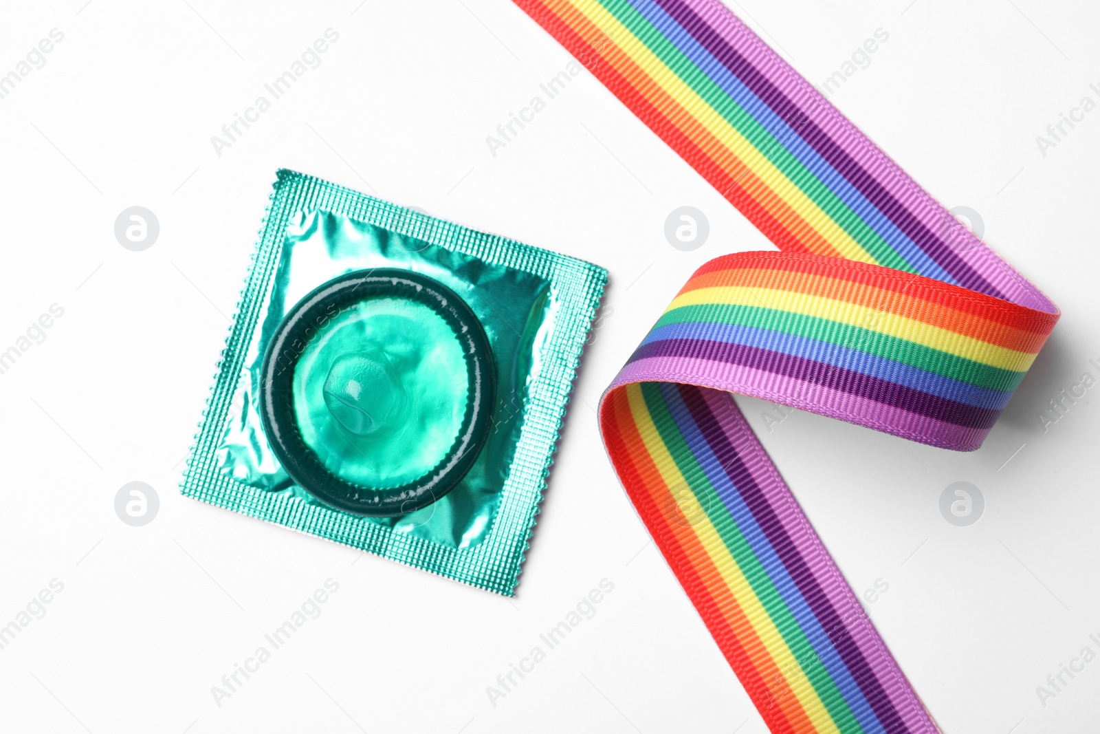 Photo of Green condom and rainbow ribbon on white background, top view. LGBT concept