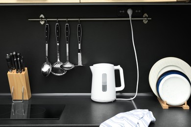 Electric kettle and kitchen utensils on black countertop