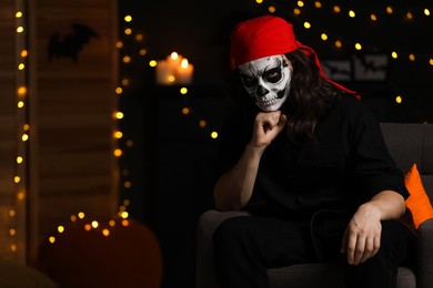 Man in scary pirate costume with skull makeup against blurred lights indoors, space for text. Halloween celebration