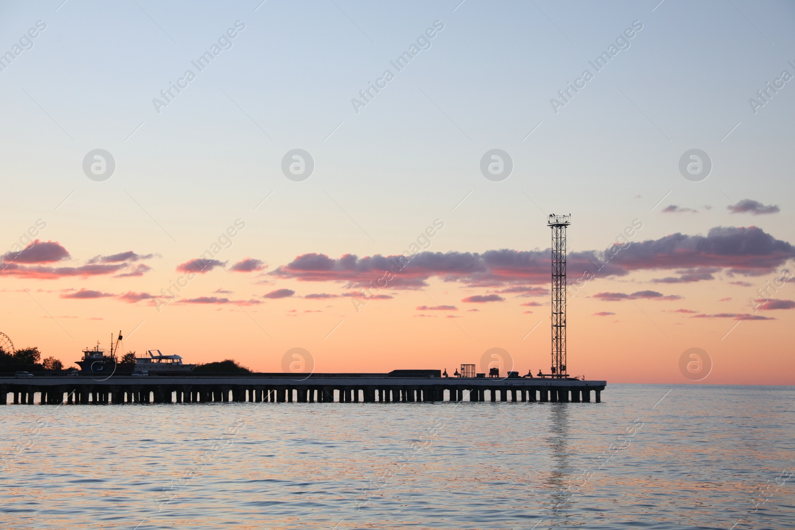 Photo of Picturesque view of pier in sea under beautiful sky at sunset