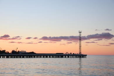 Photo of Picturesque view of pier in sea under beautiful sky at sunset