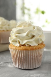 Photo of Tasty cupcake with vanilla cream on grey table, closeup