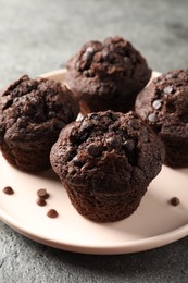 Delicious chocolate muffins on grey textured table, closeup