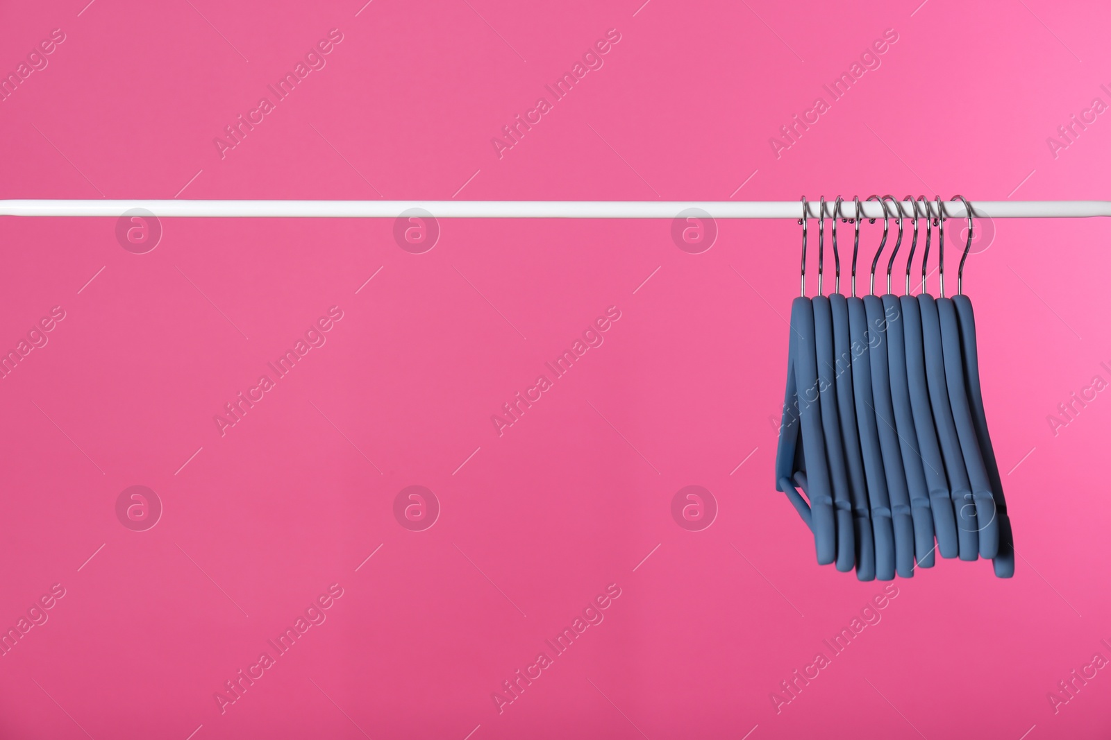 Photo of Metal rack with clothes hangers on color background, space for text