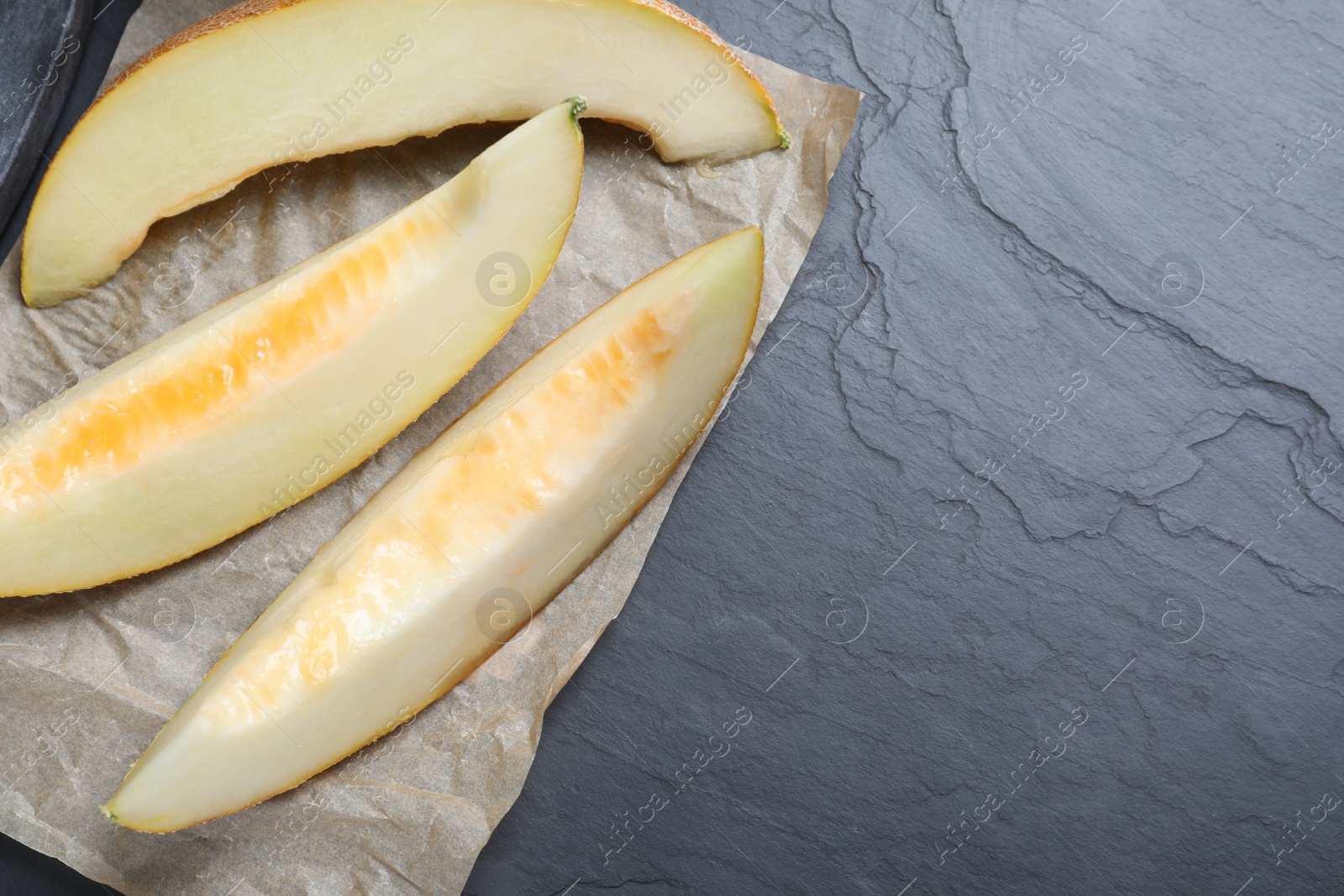 Photo of Slices of delicious honey melon on black table, flat lay. Space for text