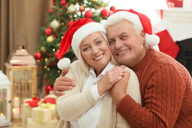 Happy mature couple in Santa hats at home. Christmas celebration