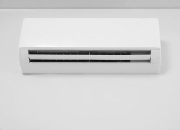 Modern air conditioner on white wall indoors, low angle view