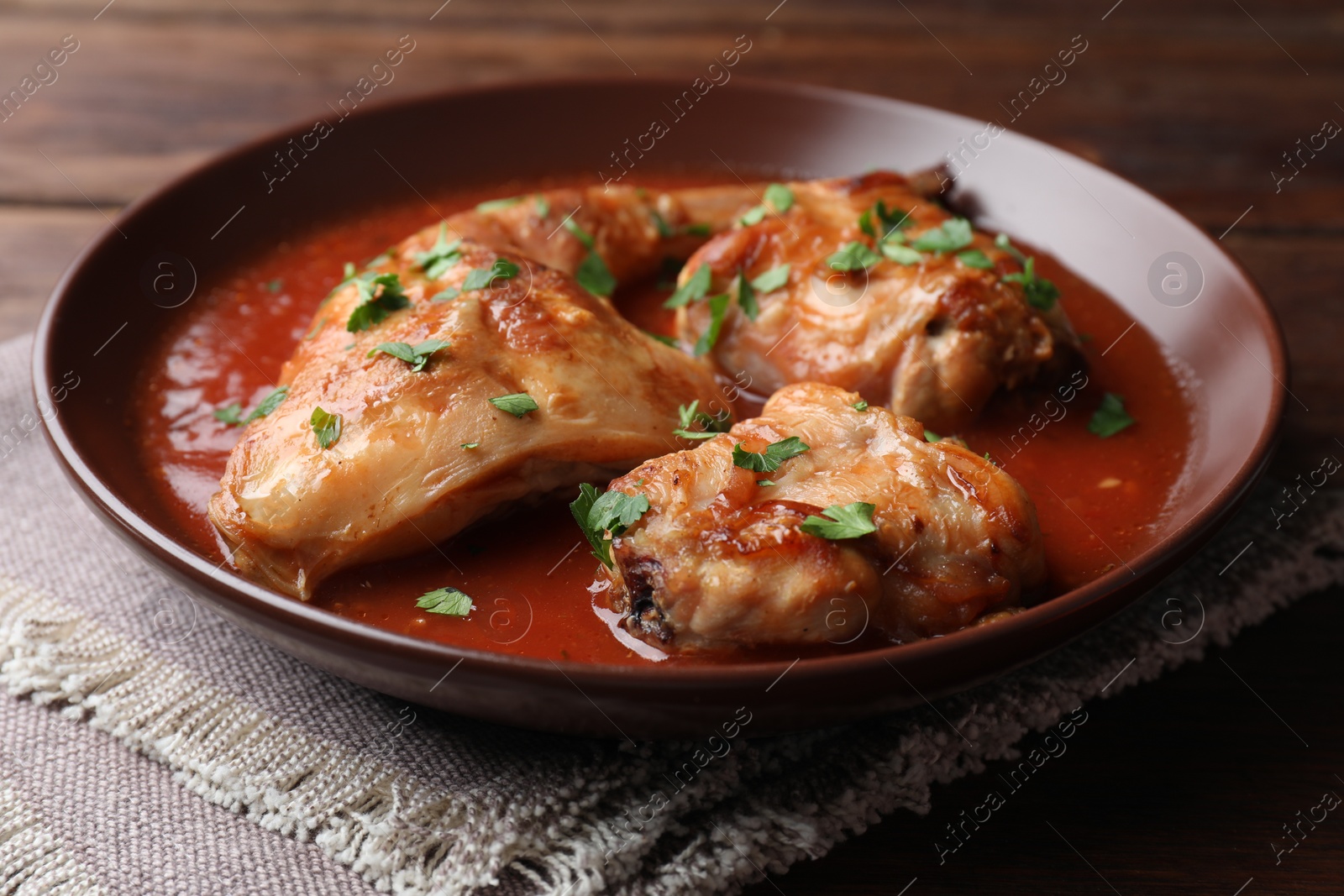 Photo of Tasty cooked rabbit meat with sauce and parsley on table, closeup